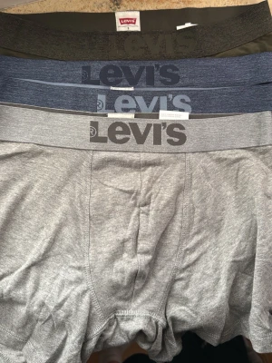 6 par kalsonger ifrån Levi (storlek S) - Säljer ett 6-pack kalsonger från Levi's i färgerna grå 2st, marinblå 2st och mörkgröna 2st. Alla har bred resår med Levi's-logga framtill. Tillverkade i mjukt och stretchigt material för skön passform. Perfekta för dig som vill ha stilrena och bekväma underkläder.