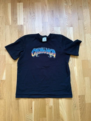 Svart Casablanca t-shirt med tryck - Snygg svart t-shirt från Casablanca med färgglatt tryck på bröstet där det står 'Casablanca' i blått, orange och vitt. Klassisk passform och rund halsringning. Perfekt för dig som vill ha en statement tee med cool design.