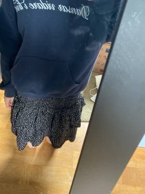 Mörkblå off shoulder tröja med texttryck - Mörkblå hoodie med vit broderad text 'Dansar vidare i livet' på bröstet. Klassisk känguruficka framtill och huva. Mjuk och skön bomullsmix, perfekt för chill dagar eller när du vill ha en avslappnad stil. Inspirerad av hov1s låt.