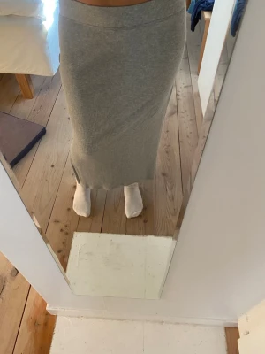 Lång kjol - Säljer en lång, grå ribbad kjol. Kjolen har en enkel och stilren design som passar perfekt till både sneakers och boots. Materialet är mjukt och stretchigt för en bekväm passform. 
