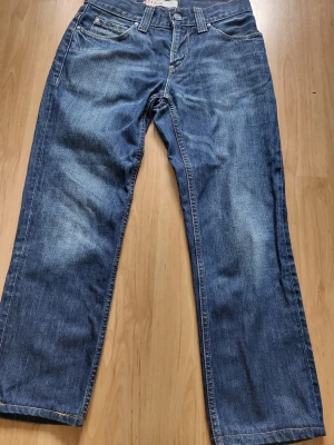 Levi's 511 Slim blå jeans - Säljer ett par klassiska Levi's 511 Slim jeans i blå denim. Jeansen har fem fickor, normal midja och raka ben. Snygga slitningar och kontrastsömmar ger en avslappnad look. Perfekta för dig som gillar tidlös stil och vill ha ett par jeans som funkar till allt. De är upp sydda de som du ser på bilderna. De är ungefär 90 cm långa och i midjan 33cm ungefär.