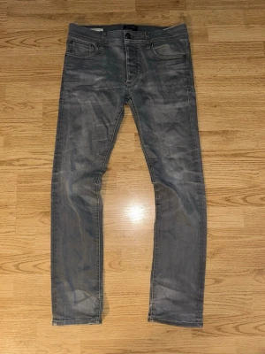 Grå slim fit jeans - Snygga grå slim fit jeans med klassisk femficksdesign och diskreta slitningar. Jeansen har smal passform och normal midja, perfekta för en trendig och avslappnad look. Materialet är mjukt och stretchigt för extra komfort.