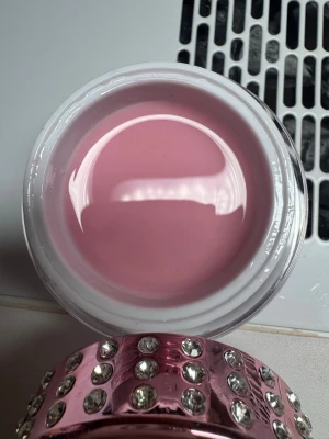 NG Starline Pink Builder Gel 30ml - Säljer en NG Starline Pink Builder Gel i en lyxig burk med strassdetaljer. Gelen har en mjuk rosa nyans och är perfekt för att bygga och forma naglar. Förpackningen innehåller 30 ml och är både snygg och praktisk för nagelentusiaster.