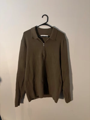 Olivgrön stickad tröja med halvzip från samsoe samsoe - Snygg olivgrön stickad tröja med halv dragkedja och krage. Tröjan har lång ärm och en avslappnad passform, perfekt för lager på lager. Materialet ser mjukt och bekvämt ut, och färgen är lätt att matcha till olika outfits.