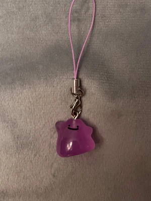 Ditto Mobilsmycke Pokemon hänge Ditto Nyckelring Pokemon  - Jättegulligt hänge med en Ditto! Den är dessutom självlysande och lyser i mörkret.   Ditto-berlocken är ca 1,5 x 1,5 centimeter. Öglan är ca 5 cm lång.  Jättefin att sätta på din mobil, väskan, ditt 3DS, Switch eller i nycklarna exempelvis! 