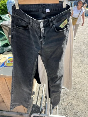 Svarta bootcut jeans från Divided H&M - Säljer ett par svarta lågmidjade bootcut  jeans från Divided H&M i storlek 36. Jeansen har klassisk femficksmodell, låg midja och dragkedja med knapp. Materialet är stretchigt för en bekväm passform och färgen är tvättad svart för en cool look.
