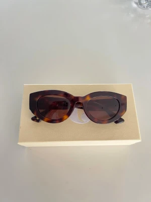 solglasögon från corlin eyewear  - Snygga solglasögon från Corlin eyewear i modell ”Ines tortoise Brown” med brunmelerad båge och mörka linser. Bågarna har ett stilrent C på sidan och är tillverkade i syntetmaterial. Perfekta för soliga dagar och ger en trendig look.