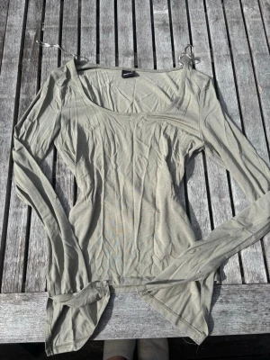 Beige långärmad topp med v-ringning - Snygg grön långärmad topp med v-ringning och figurnära passform. Tillverkad i mjuk bomull som känns skön mot huden. Den är funkar perfekt som ett basplagg i vardagen men också som en verktyg för att styla och klä upp🤗