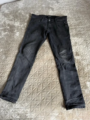 Svarta slim fit jeans från Replay - Svarta slim fit jeans från Replay med diskreta slitningar. Jeansen har slim fit, storlek L 30, W 30. 