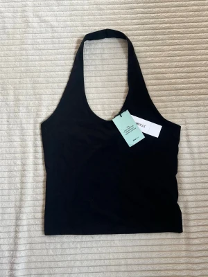 Halterneck top - Svart halterneck top ifrån Ginatricot i storlek M, helt oanvänd med prislapp på🌸 Är i 95% Bomull, 5% Elastan. Toppen är öppen i ryggen och har en figurnära passform