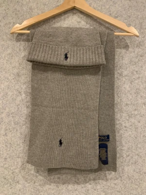 Polo Ralph Lauren Merino wool Beanie&Scarf - Säljer en grå Polo Ralph Lauren mössa och Halsduk i Marino ull och grå färg. Köpte den från Zalando för 1700kr, den e knappt använd. Skriv gärna vid intresse