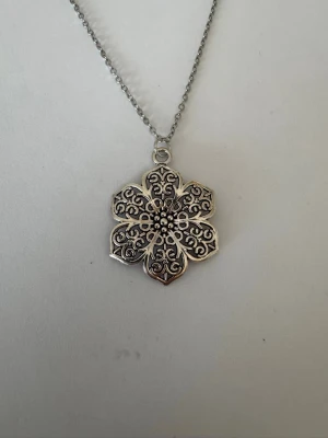 Halsband mönstrad blomma - Halsband som inte är i äkta silver/guld. Kedja är oftast 50cm men kan ibland komma i 45cm. Kedja är rostfritt stål, berlock oftast i zinklegering men kan även det i vissa fall vara rostfritt stål. Be gärna om mått på berlock om detta är viktigt då bilderna är missvisande när det gäller hur stora dom är! 🌹❤️  Allt är nytt.  Bud accepteras inte 🥰🌹