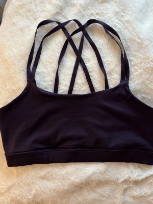 Lila sport-bh med korsade band - Lila sport-bh med tunna korsade axelband i ryggen. Bh:n har en enkel, stilren design utan vaddering. 