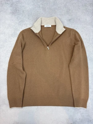 Beige stickad tröja Gran Sasso - Stickad tröja i beige från Gran Sasso med halv dragkedja och ribbad, kontrasterande krage i ljusare beige. Långärmad modell med ribbade muddar och nederkant. Perfekt för lager på lager och snygg till jeans eller chinos.