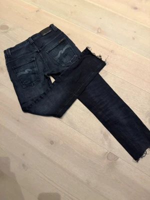 Svarta jeans från Nudie - Svarta jeans från Nudie!! Perfekta för dig som gillar en stilren och modern vibe. Snygga slitningar och se modellen och storlek på sista bilden!! Jeansen är klippt där dere så sitter dom är i mellan L 32 och 30, därav priset!! 