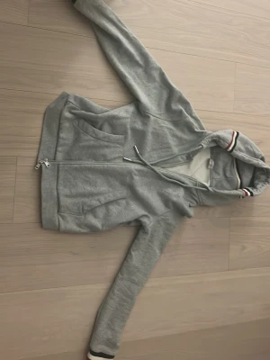 Grå Moncler hoodie med dragkedja - Fet hoodie med nypris 4000 kr. Köptes för 2 års sen och används ett par gånger. Inga fel med den men säljs för att jag växt ur den. Den är äkta och mitt pris är förhandlingsbart vid snabb affär.