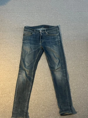 Blå slim fit jeans med slitningar - Snygga blå slim fit jeans från tiger of Sweden midja 29 och längd 30 skulle jag säga. Med  tvättade detaljer. Klassisk femficksmodell med knappgylf och kontrastsömmar. Perfekta för en avslappnad och trendig look.