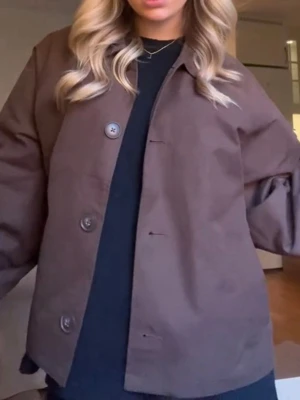 Brun trenchcoat  - En så snygg kort brun trenchcoat från NA-KD. Sparsamt använd. Jag skulle säga att den är stor i storlek eftersom jag vanligtvis brukar ha 34/36 i jackor men i denna kan jag ha 32. Jag skulle säga att den är ganska så lång i ärmarna💕