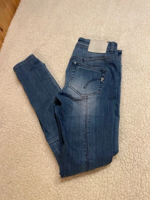 Dondup Jeans  - Snygga blå slim fit jeans från Dondup med diskreta slitningar och markerade sömmar vid knäna. Jeansen har klassiska fickor fram och bak samt en liten metall-detalj på bakfickan. Perfekta för en trendig och avslappnad look. Mått, Innerbenslängd ca 79cm och midja ca 40cm. 