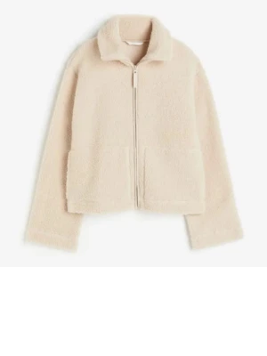 Beige teddyjacka med dragkedja - Mysig beige teddyjacka med dragkedja framtill och två stora fickor. Jackan har en klassisk krage och är gjord i fluffigt teddy-material som ger en trendig och avslappnad look. Perfekt för att hålla värmen under kyliga dagar.