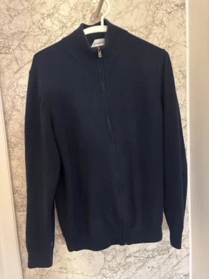 Helzip 100% Kashmir  - Mörkblå ziptröja i 100% Kashmir från Lawrence grey. Tröjan har blivit lagad men syns väldigt lite (se sista bild) pris kan diskuteras vid snabb affär