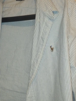 Randig skjorta från Ralph Lauren M - Klassisk skjorta från Ralph Lauren i vitt och blått med tunna ränder. Custom fit-modell med broderad logga på bröstet. Tillverkad i bomull och har långa ärmar samt knappar framtill. Perfekt för en stilren look.