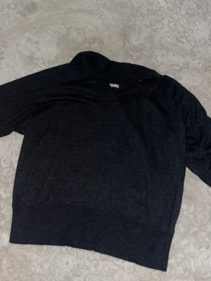 Mörkgrå tröja med krage - Mörkgrå tröja med mjukt material och klassisk krage. Tröjan har en avslappnad passform och ribbad nederkant. Perfekt för dig som gillar stilrena och enkla plagg.