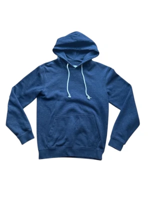 Blå hoodie från Pier One - Blå hoodie från Pier One med klassisk känguruficka och vita dragsnören i huvan. Tillverkad i mjukt bomullsmaterial som känns skönt mot huden. Perfekt för en avslappnad och stilren look.