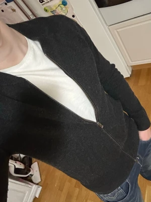 Svart ziptröja från massimo dutti - Snygg svart ziptröja med ribbade muddar och hel dragkedja framtill. Tillverkad i mjuk ullmix som känns skön mot huden. Perfekt att slänga på sig över en t-shirt för en clean och enkel look.