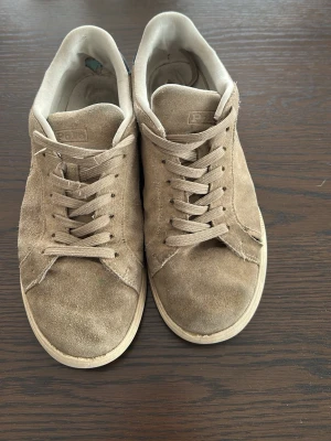 Beige mockasneakers från Polo - Snygga beige sneakers från Polo i mocka med klassisk låg profil och matchande beige snörning. Yttersulan är i gummi och har Polo-loggan undertill. Perfekta för en avslappnad streetwear-look. Pris kan diskuteras 