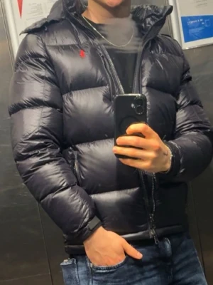 Svart Gorham jacka från Ralph Lauren - Lite schysstare svart Gorham pufferjacka från Ralph Lauren storlek S. Perfekt för kalla dagar och tvär skön att bära. Klassisk design som funkar till det mesta så att säga. Har ni några funderingar, tveka inte att höra av er 🤝🤩