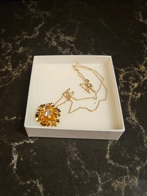 Caroline Svedbom Necklace Blossom Gold - 1 st Blossom Necklace Gold från Caroline Svedbom i nyskick. Kommer i originalask  Storlek: 2,4 x 2,4 cm + 50 cm kedja Mässing med plätering: 18K Guld Världens högsta kvalitet på kristaller  Nypris 995 kr