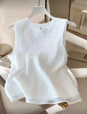 Vit ärmlös linnetopp - Säljer en fräsch vit linnetopp med rund halsringning och lätt strukturerat tyg. Toppen är ärmlös och har en luftig passform som passar perfekt till varma dagar. Enkel och stilren design som är lätt att matcha med olika outfits.