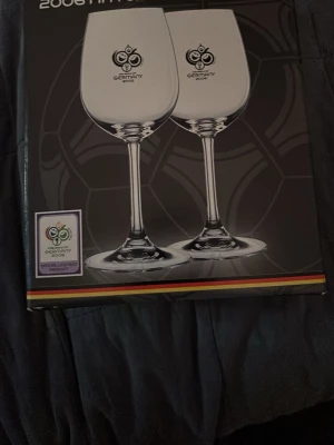 FIFA 2006 vinglas i originalkartong - Två stora vinglas i glas med FIFA World Cup Germany 2006-logga. Levereras i originalkartong med officiell licens. Perfekt för samlare eller fotbollsälskare. Tillverkade i Tyskland. Och helt nya