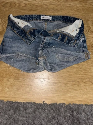 Blå jeansshorts från Zara - Snygga blå jeansshorts från Zara med klassisk femficksdesign och slitna detaljer. Shortsen har låg midja och är tillverkade i bomull med slitningar. Jättefint skick, priset går att diskutera ❤️❤️❤️