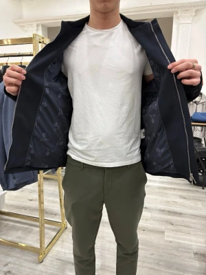 Loro Piana Navy Windbreaker - Loro Piana Navy Windbreaker / Pyjamajacka – Ny med lappar  Helt ny med lappar, mörk navyblå färg. Lättare windbreaker/regnjacka (inte vinterjacka).  Storlek XL – kan även passa mindre beroende på önskad passform. För referens: jag är 180 cm och brukar ha M, och den sitter bra oversized.  Kommer med kvitto och alla originaltillbehör.  Meddela gärna om du har frågor 