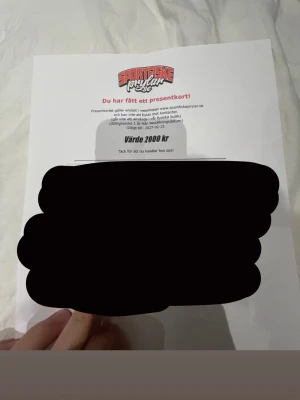 Presentkort Sportfiskebutik 2000 kr - Presentkort till sportfiskebutikens webbshop, värde 2000 kr. Kortet är tryckt på vitt papper med butikens logga i rött och svart. Kan endast användas online på sportfiskeprylar.se. Perfekt för dig som gillar fiske och vill handla utrustning.