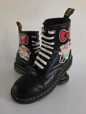 Dr. Martens x Sanrio 1460 (Limited Edition) - Stl 38 - Säljer ett par supergulliga, limited edition Dr. Martens från det eftertraktade samarbetet med Sanrio! 🎀  Klassisk 8-hålsmodell med unika Hello Kitty & Friends-tryck och söta detaljer som färgade snörhål.​                 Skick: ♡ Fint helhetsintryck, sparsamt använda. ♡ Lite ytslitage fram på tårna. ♡ Fina sulor med mycket liv kvar. ♡ OBS: En spricka i lädret vid ett rosa snörhål. Stör ej funktionen men därav låga priset!  ​Info: ♡ Stl: 38 (UK 5) ♡ Mod: 1460 HK+F