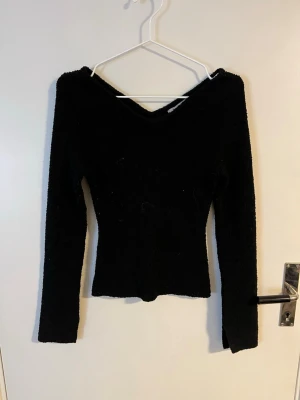 Svart fluffig tröja från H&M - Mysig svart långärmad tröja från H&M med fluffig textur och v-ringad hals. Tröjan är figurnära och har en enkel, stilren design som passar perfekt till jeans eller kjol.