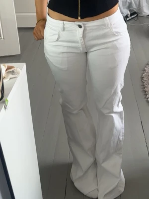 Vita bootcut jeans med hög midja - Säljer ett par vita bootcut jeans med låg midja. Jeansen har vida ben och stängs med knapp och dragkedja framtill. Använd 2 gånger. 