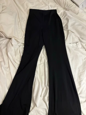 Svarta utsvängda byxor från SHEIN - Svarta utsvängda byxor från SHEIN i storlek XS (EU 34). Byxorna har hög midja och vida ben, vilket ger en snygg och trendig siluett. Perfekta att styla med crop tops eller oversized tröjor. Materialet är mjukt och stretchigt för extra komfort.