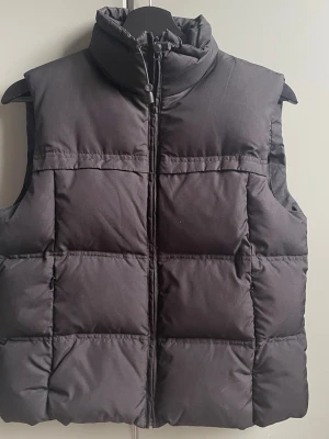 Svart dunväst - Snygg svart dunväst med quiltad design och hög krage. Över höger ficka finns det ett hål (se bild 5-6). De syns nästan inte om man inte kollar noga🩷
