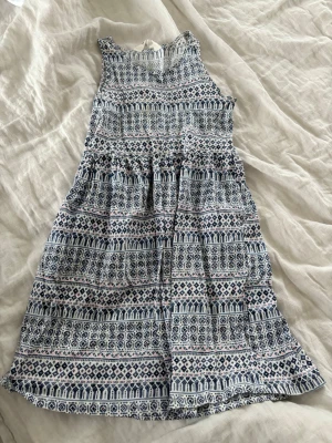 Mönstrad blåvit sommarklänning - Säljer en ärmlös kortklänning i blått och vitt med ett snyggt geometriskt mönster. Klänningen har rund halsringning och är tillverkad i ett lätt och skönt bomullstyg, perfekt för varma dagar. Passformen är normal och modellen är luftig och bekväm.🤍🩵💓
