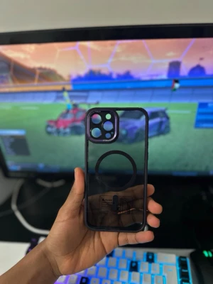 Transparent MagSafe mobilskal svart kant - Snyggt transparent mobilskal med svart kant och MagSafe-kompatibilitet. Skalet har en tydlig cirkel på baksidan för MagSafe och stora utskärningar för kamera och knappar. Tillverkat i tålig plast som skyddar mobilen utan att dölja designen.