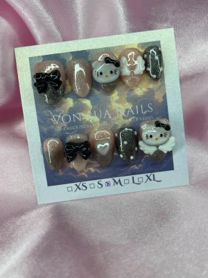 KittyNoir (M);Short Almond - Handgjorda press-on naglar i en kort mandelform med glitter, svart och nude färg. Dekorerade med 3D-motiv som Hello Kitty, rosetter och hjärtan. Perfekt för dig som gillar söta och unika designs.M: 16 mm, 12 mm, 12,5 mm, 11,5 mm, 10 mm