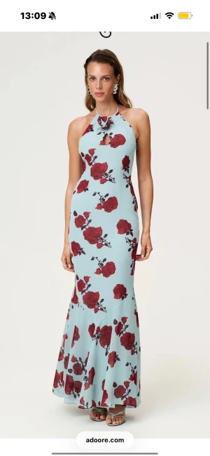 ROZZANO MAXI DRESS från Adoore - Långklänning med ljusblå bas och stora röda rosor, halterneck med knyt och liten öppning framtill. Den är helt ny men lappen kvar. Köpt på en utförsäljning där man inte kunde prova storleken, därmed för liten för mig!💕🙌🏼