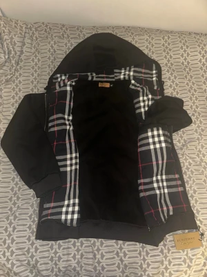 Svart Bb hoodie - Säljer en svart hoodie från Burberry . Storlek står 2XL men den sitter som L om du ör 180+ kommer den sitta perfekt. Den har en innre ficka vid höger sidan. Om du vill diskutera pris eller få mer detaljer på hoodien är det bara att skriva.