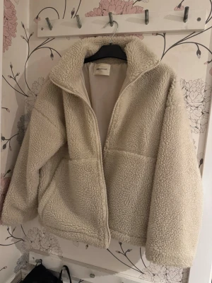 Beige teddyjacka från Carin Wester - Mysig teddyjacka i beige från Carin Wester med hög krage och dragkedja framtill. Jackan har en avslappnad passform och är gjord i fluffigt teddy-material som håller dig varm. Perfekt för att ge din outfit en chill vibe under kalla dagar.💗