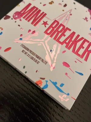 Jeffrey Star Mini Breaker ögonskuggspalett - Mini Breaker ögonskuggspalett från Jeffree Star Cosmetics med nio intensiva färger i både matta och skimrande nyanser. Färgerna inkluderar orange, lila, rosa, guld, brun och gult. Paletten har spegel och färgstark design med stjärnprägling i varje skugga.