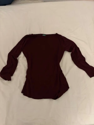 Vinröd långärmad topp  - En enkel och stilren vinröd långärmad topp. Toppen har en rund halsringning och är gjord i ett mjukt, tunt material som känns skönt mot huden. Perfekt att matcha med jeans eller kjol för en clean look.